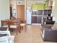 fotel, stół z krzesłami, aneks kuchenny, lodówka