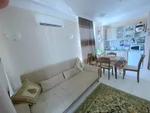 aneks kuchenny, sofa, chodnik, stół z krzesłami